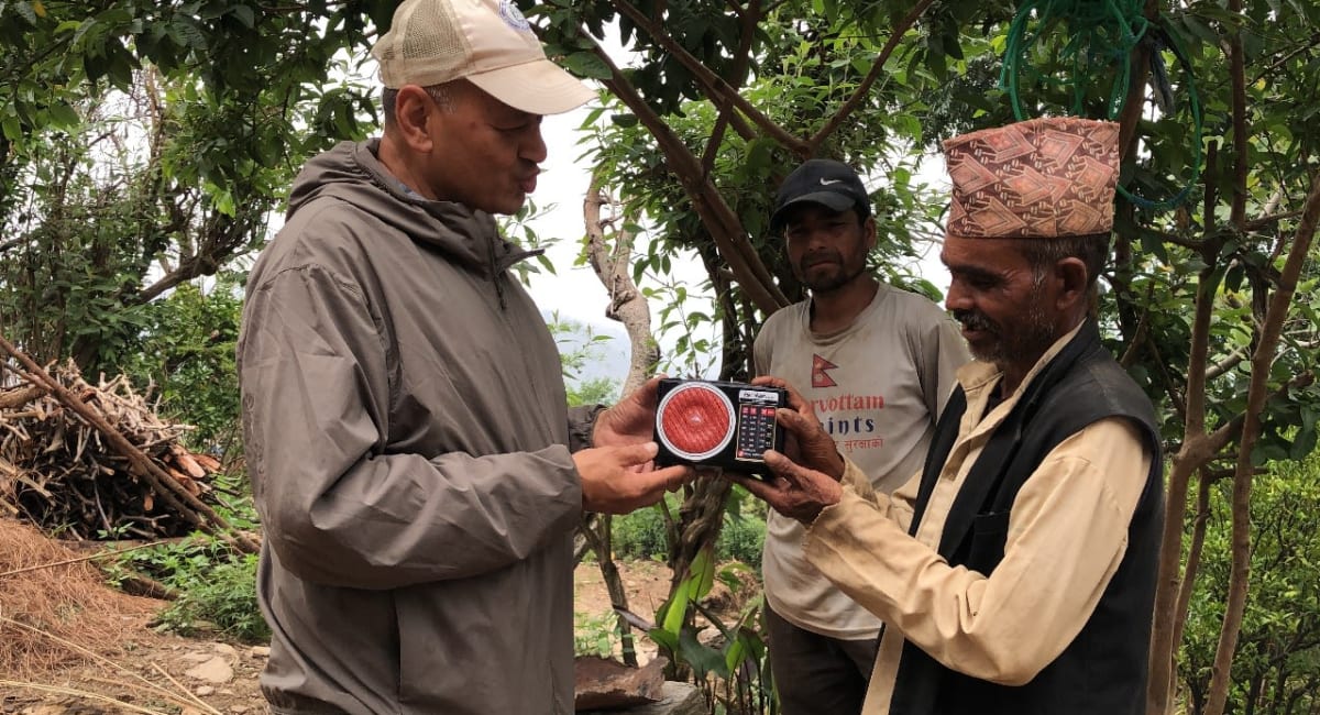 Vijay, Director of Afno FM in Nepal, presents a radio to a male listener.