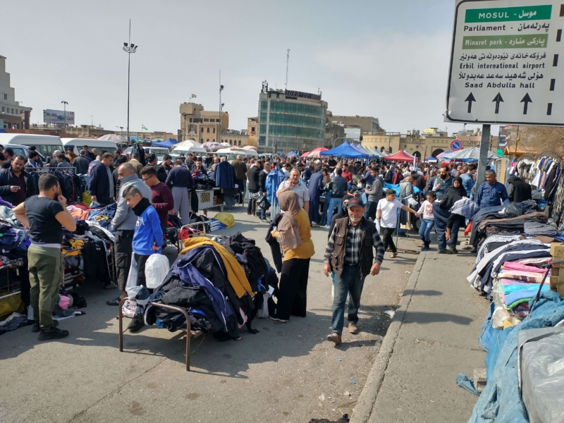 Busy market in Iraq with stalls full of clothes.