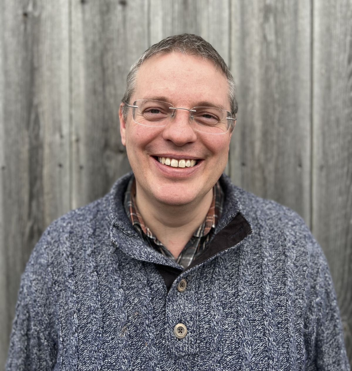 A smiling headshot of Neil, Feba's Head of International Ministry. He has short grey hair, clear rimmed glasses and is wearing a blue knit jumper.
