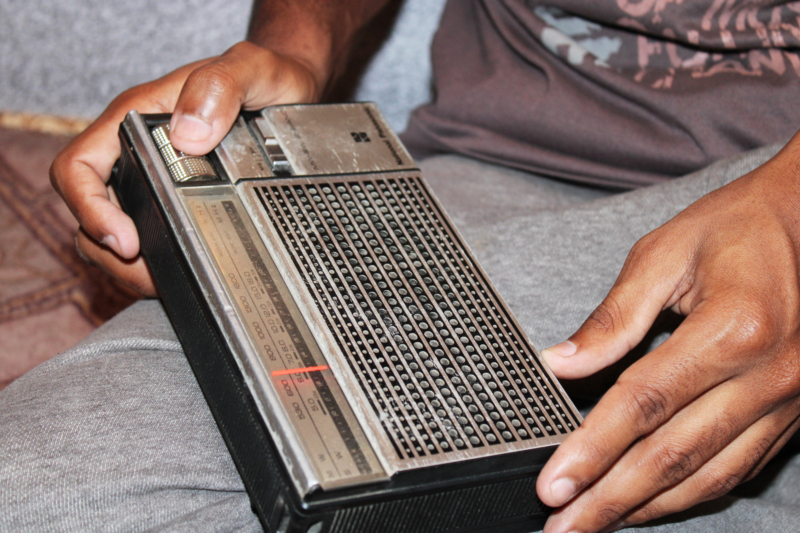 Close up of a man's hands holding a radio in Pakistan.
