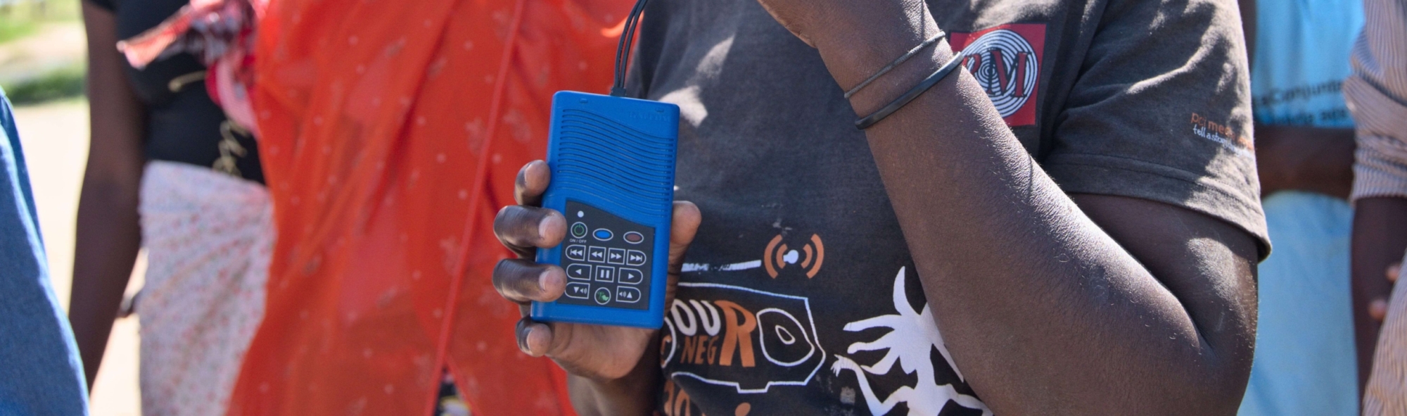 A Radio Wimbe listener in Mozambique holding a blue portable audio device.