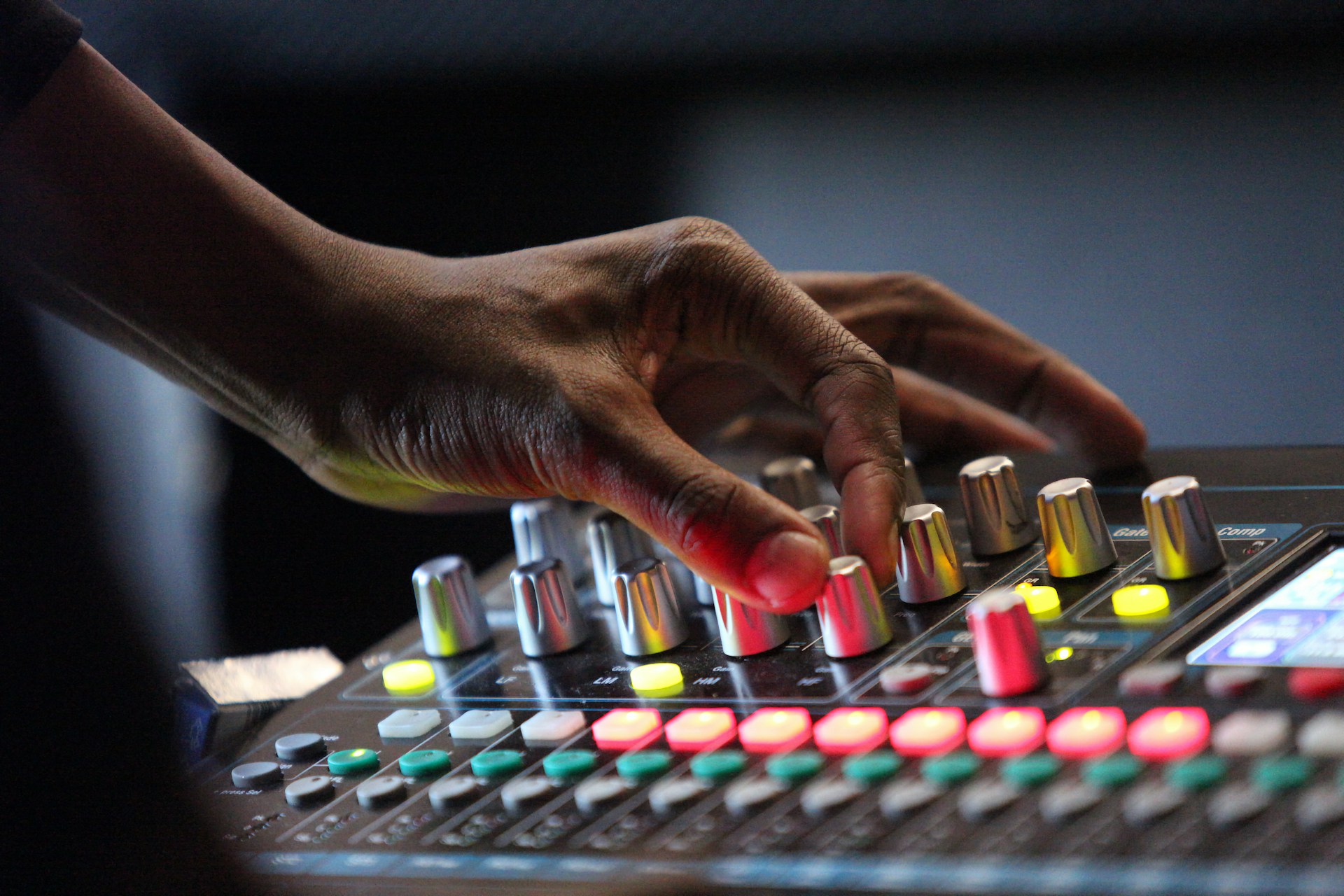 A close up shot of a man turning the dials on a sound desk.