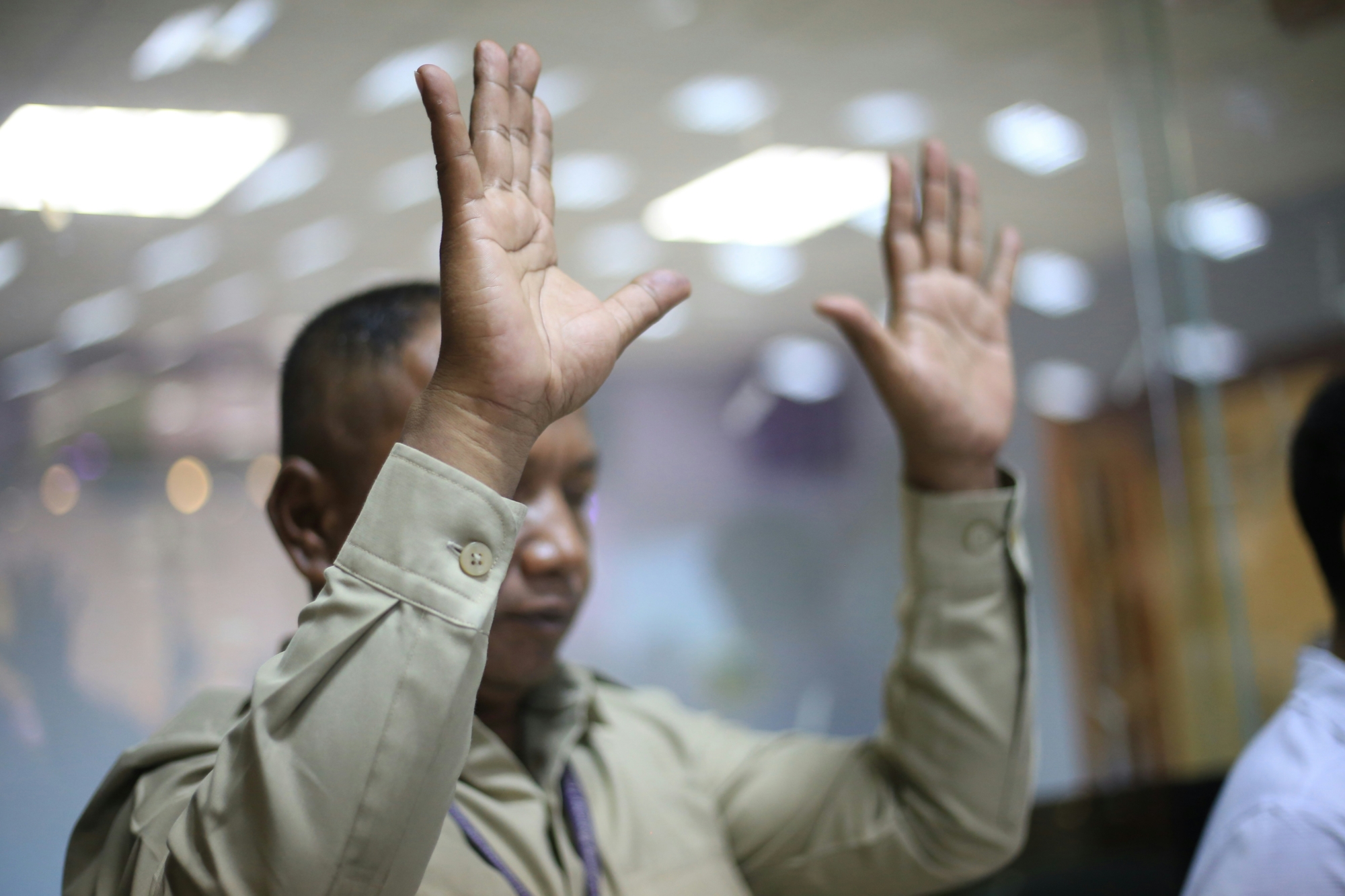 A man in Cambodia with his hands raised in worship.