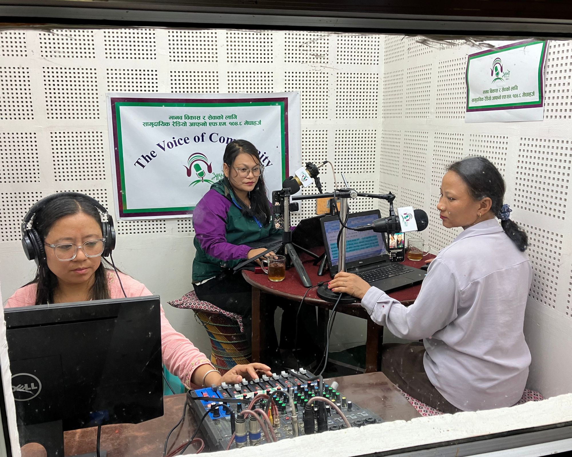 Three female members of the Afno FM team recording radio programmes in their studio in Nepal.