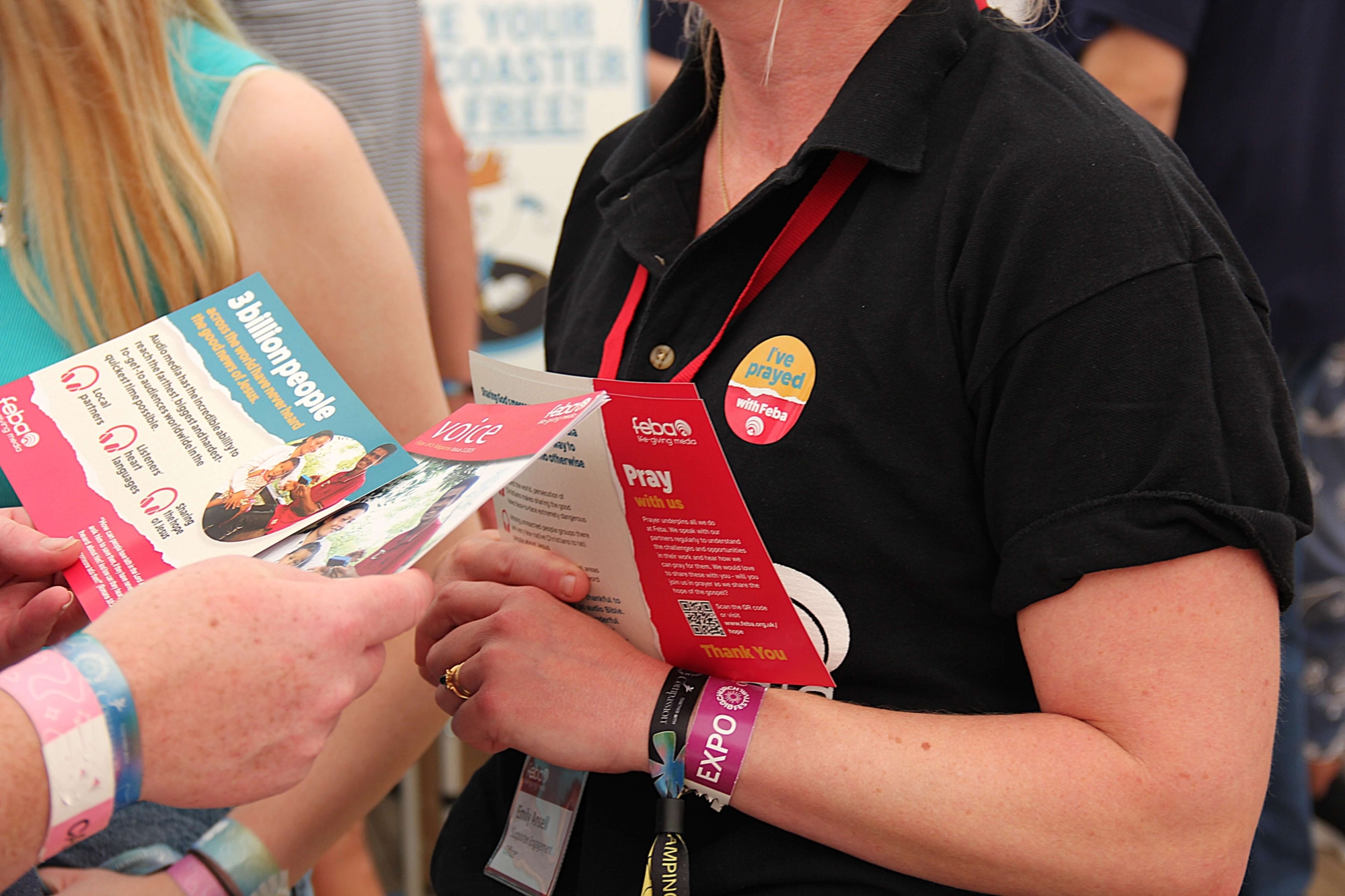 A close up shot of a Feba staff member giving out leaflets at Big Church Festival to an attendee.