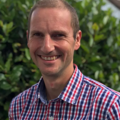 Headshot of Ben Martin, the church leader at St Margarets. Ben is wearing a red and blue check shirt and has short shaved brown hair.