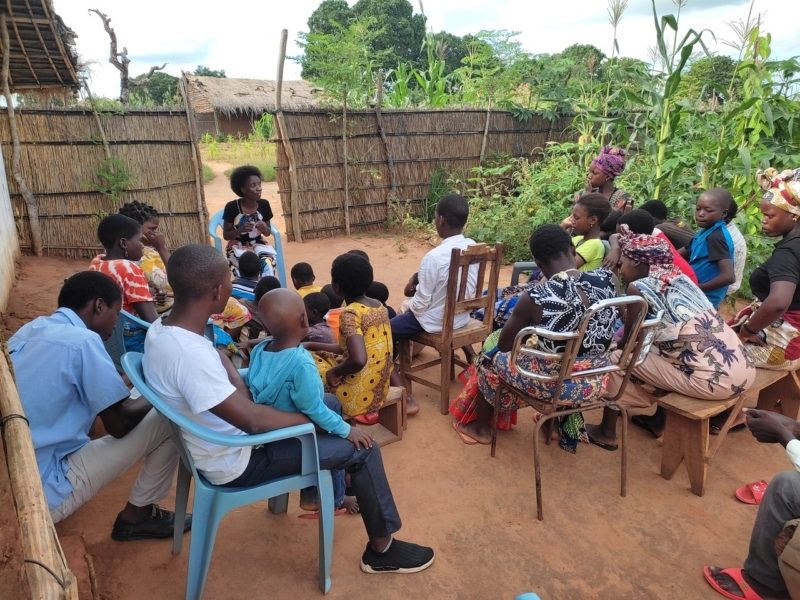 A group of people sitting together studying the Bible in a village in Mozambique.