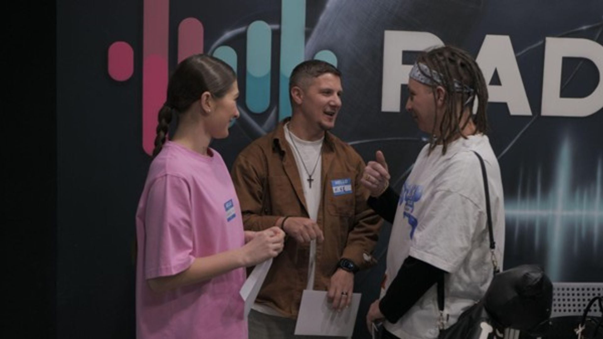 A group of three - one woman in a pink tshirt and two men, one with a short dark hair and one with dreadlocks - stand together chatting at the FEBC Ukraine radio studio.