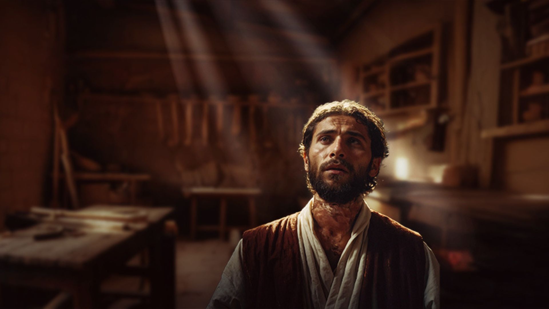 An interpretation of Joseph, father of Jesus standing in a carpenters workshop looking up as a shaft of light falls on his face.