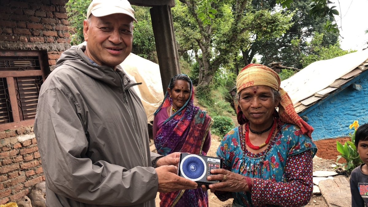 Vijay, Director of Afno FM in Nepal, presenting a radio to a female listener in a rural village.