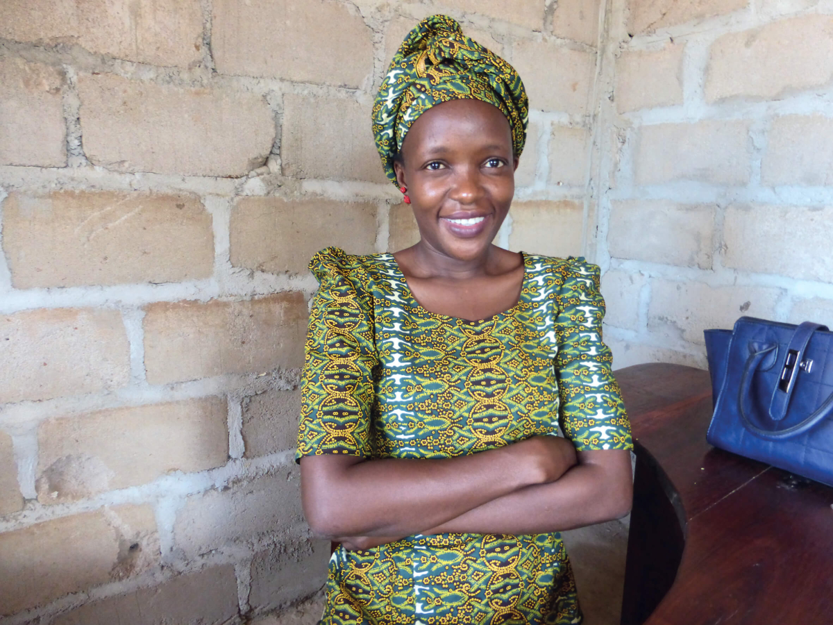 Farida, Radio Wimbe's Station Manager, smiling at the camera. She is wearing a green headscarf and matching dress.