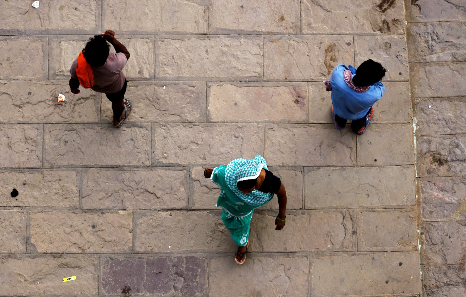 Ariel shot of three people walking along a cobbled street.